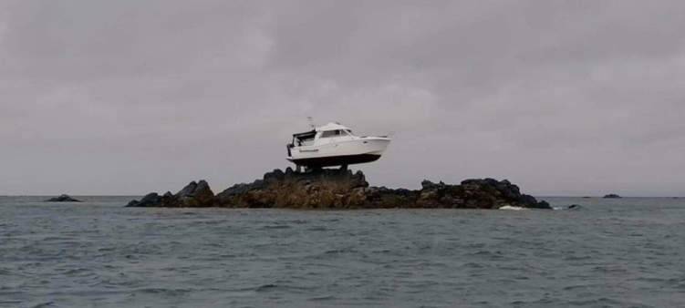 قارب معلق على صخرة في عرض البحر.. ما قصته؟