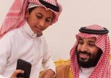 طفل يتكئ على كتف "ولي العهد" ويلتقط صورة سيلفي